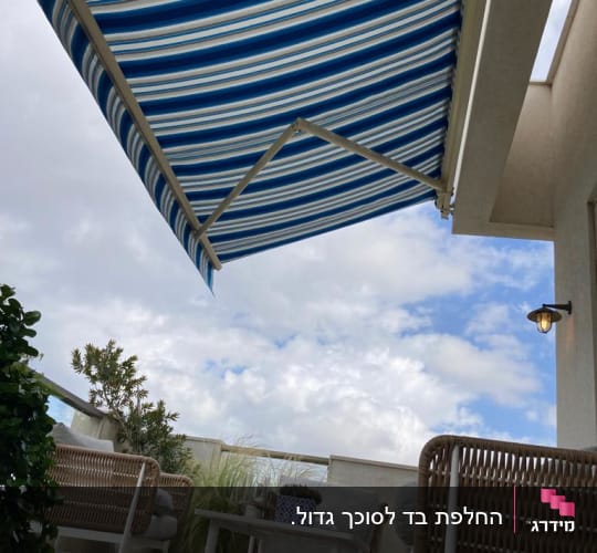 סוכך זרועות מתקפל עם בד פסים כחול לבן במרפסת